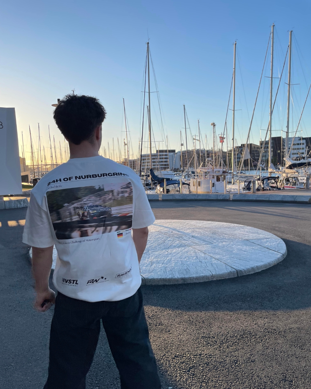 RINGWEAR 24H of Nürburgring tee worn at a marina roundabout with sailboats at golden hour